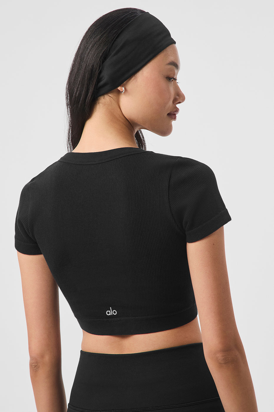 Front view of the black lace crop top on a model, highlighting its scoop neckline.