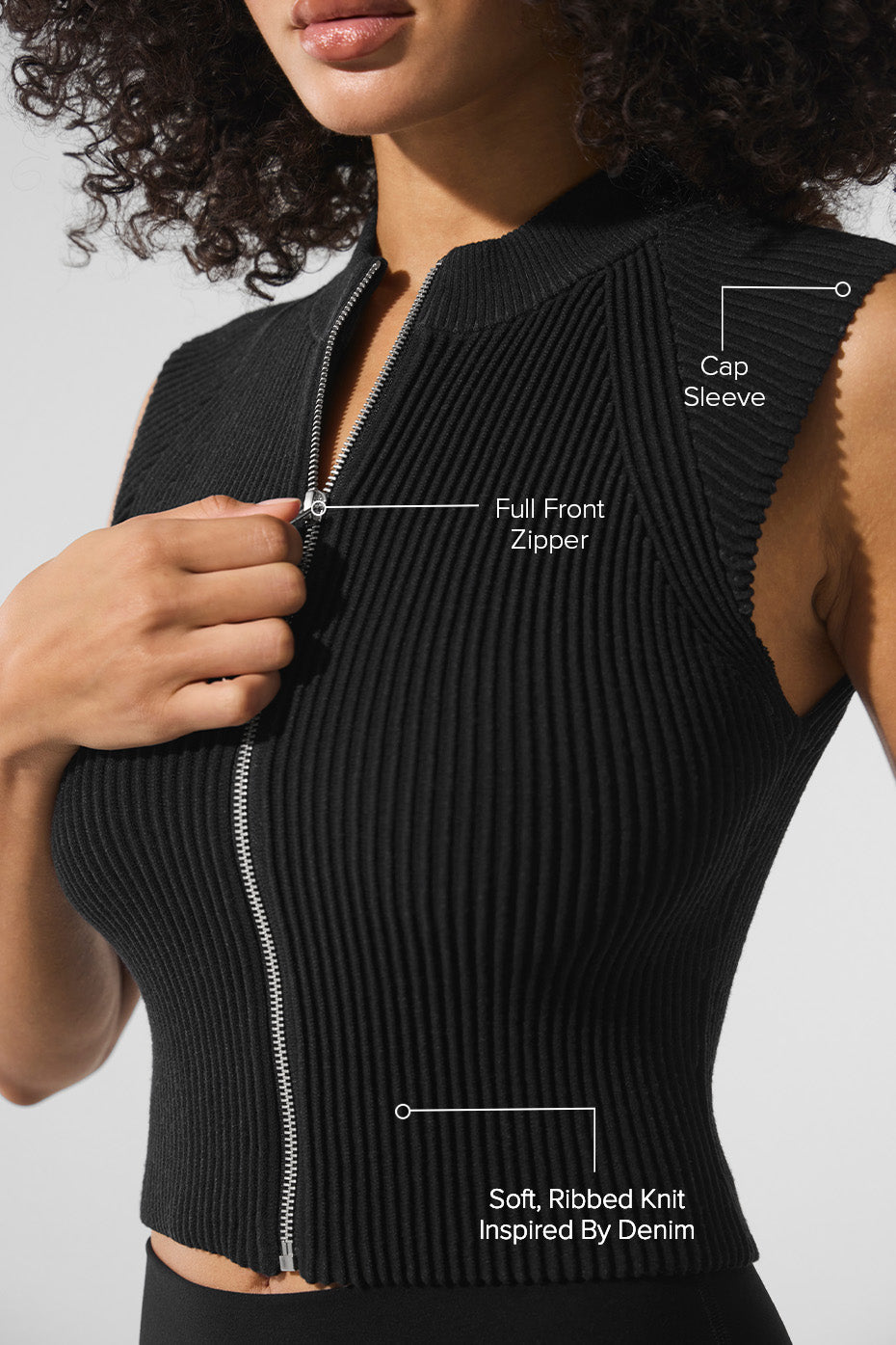 Side angle showing structured fit of black zip-up tank top, matched with wide-leg trousers