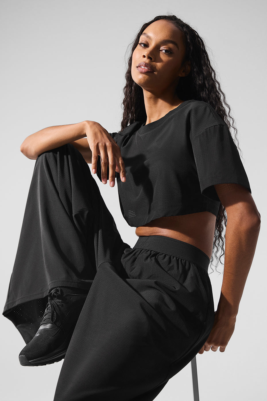 Front view of black cropped mesh top styled with high-waisted jeans