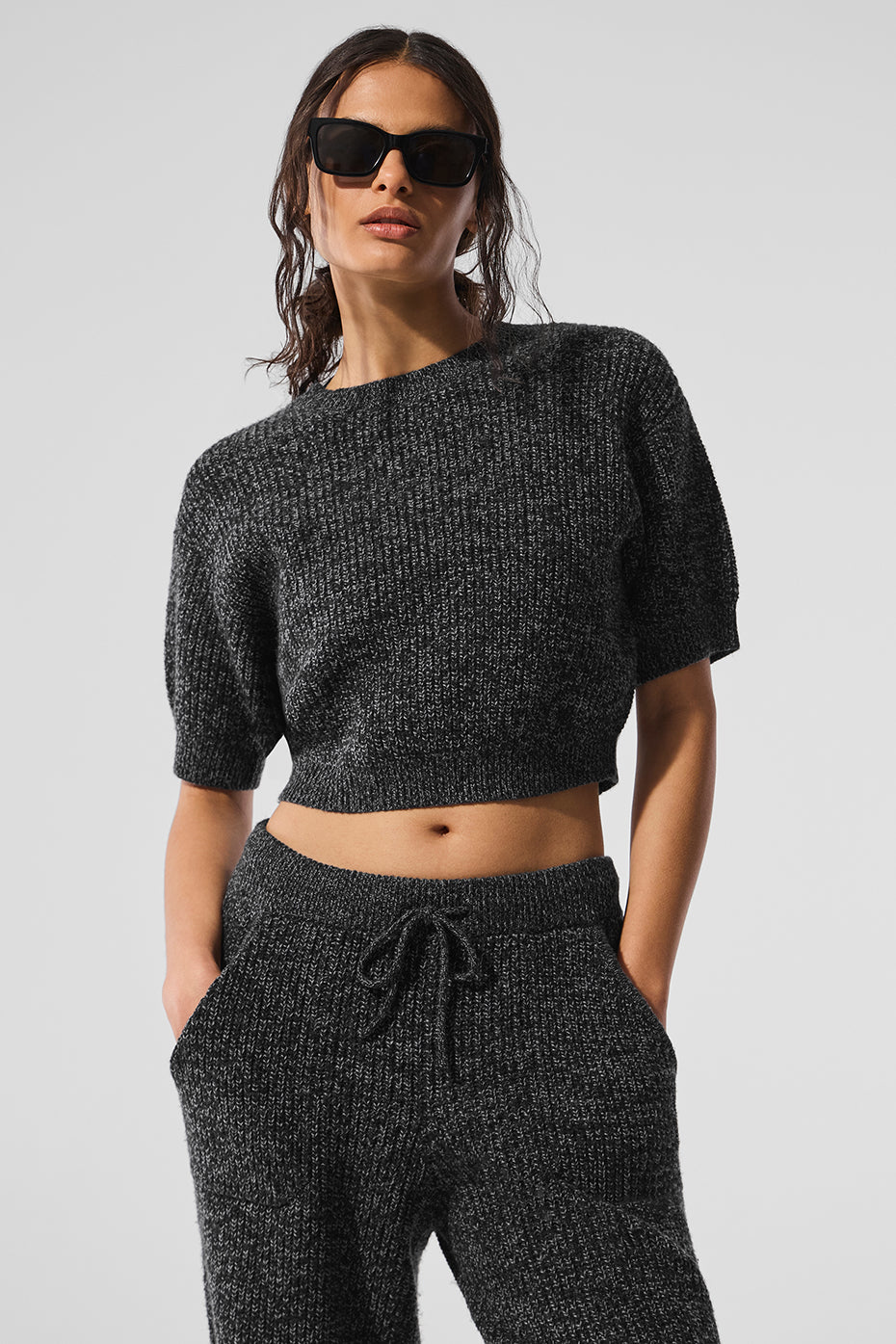 Model wearing black marl sweater with rolled sleeves in urban cafe setting