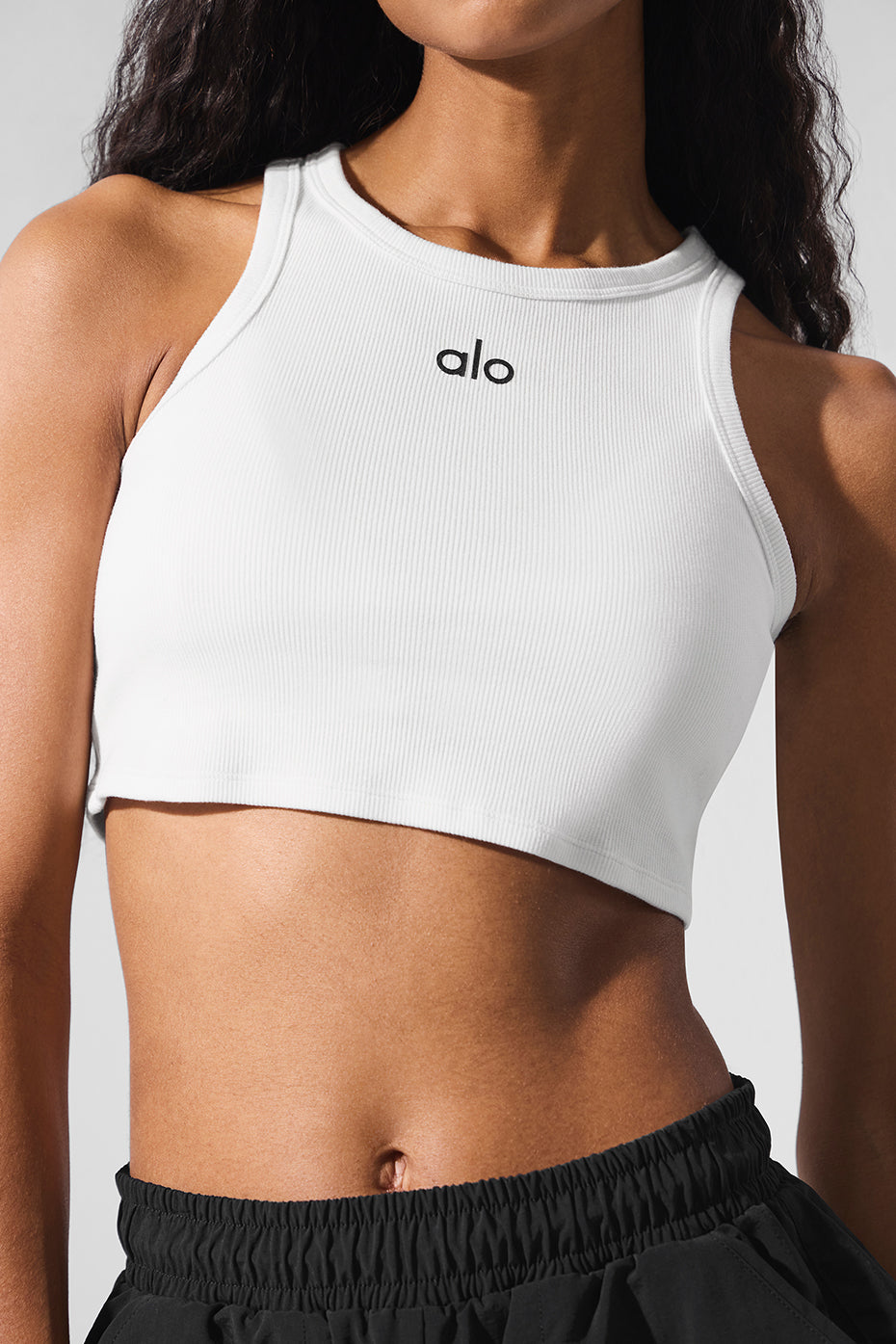Model wearing Aspire white tank top with high-waisted shorts.