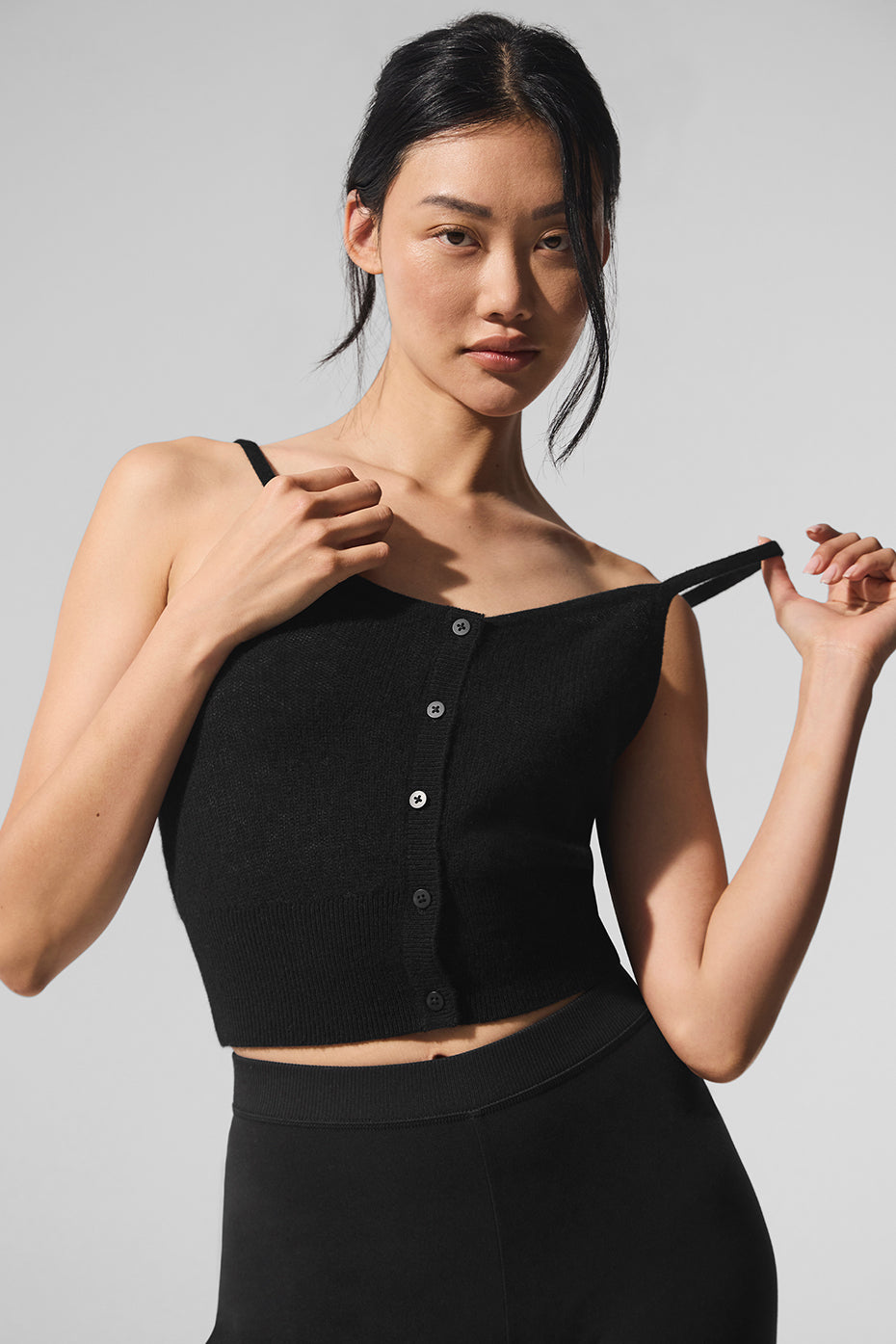 Front view of the sheer cashmere tank top in black, showcasing button details.