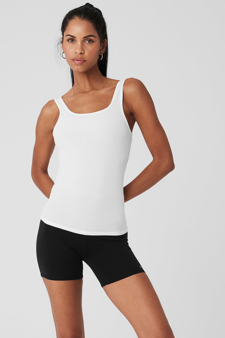 Woman wearing white scoop neck tank top with jeans, urban daytime outfit