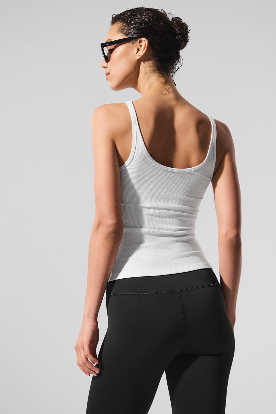 Model wearing a white ribbed tank top paired with leggings for a relaxed look