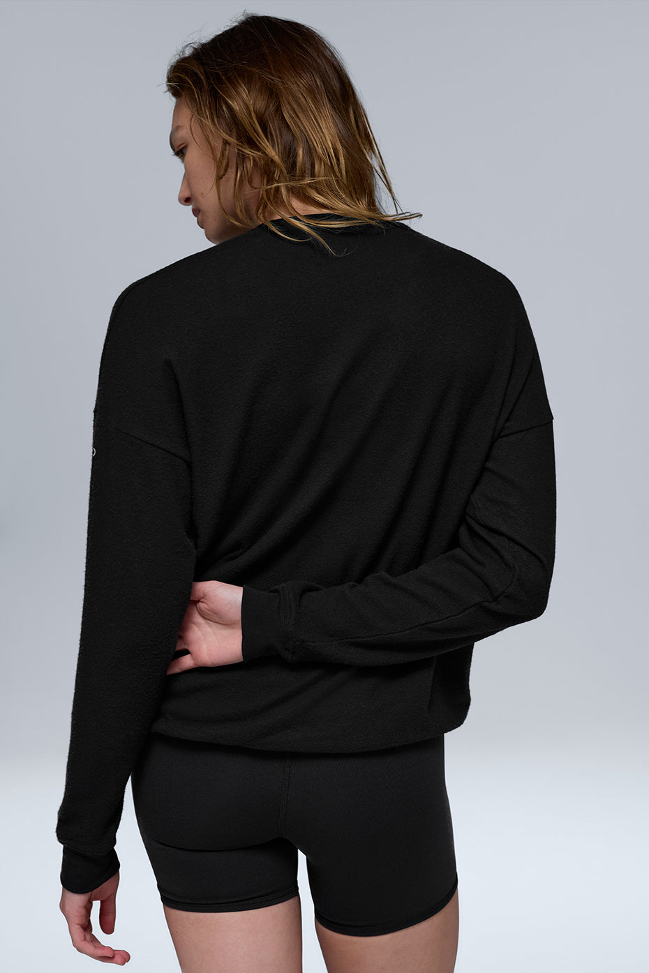 Model wearing black casual pullover with jeans in urban setting