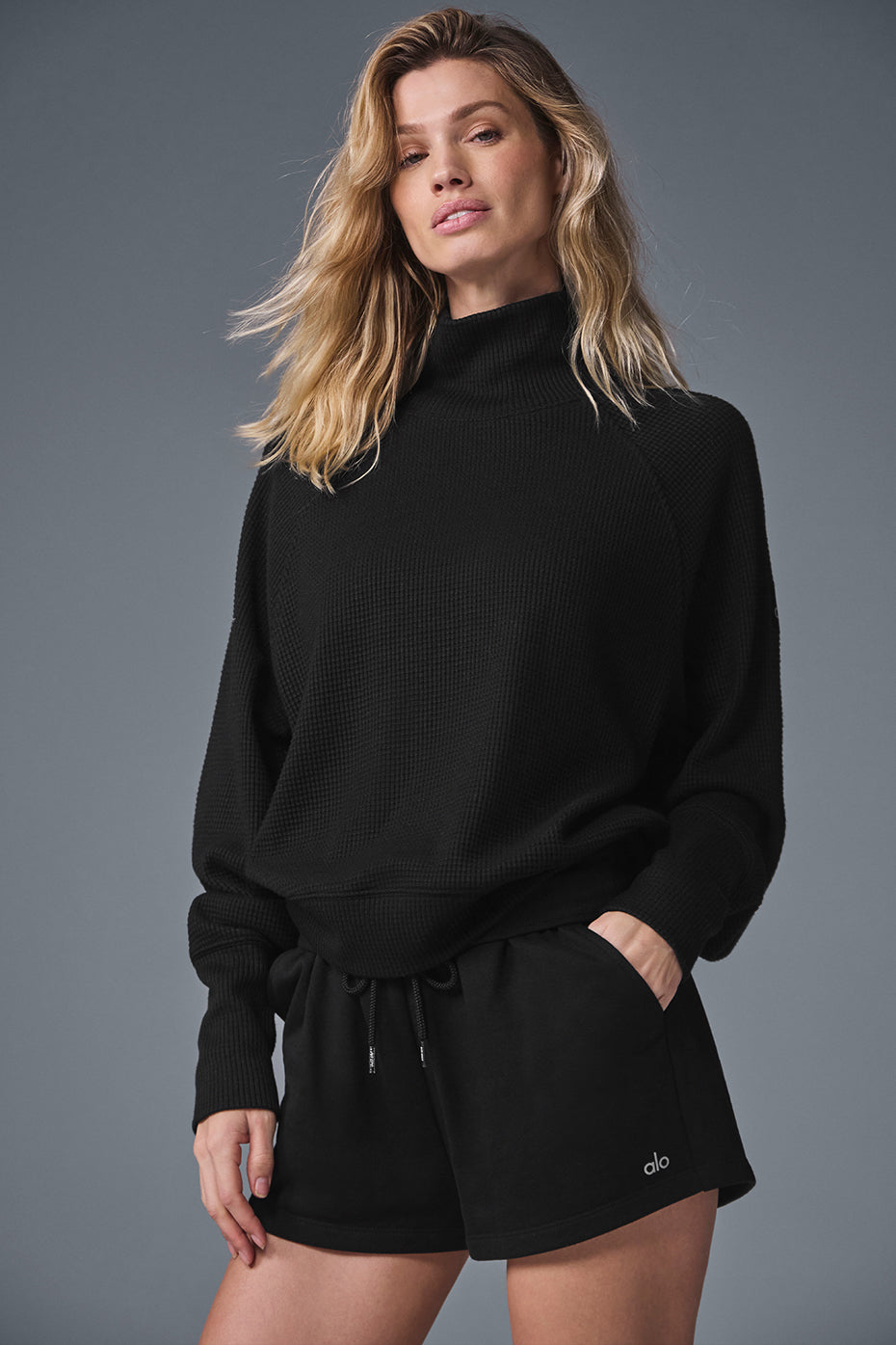 Black mock neck long sleeve top draped on a hanger, showcasing waffle knit texture