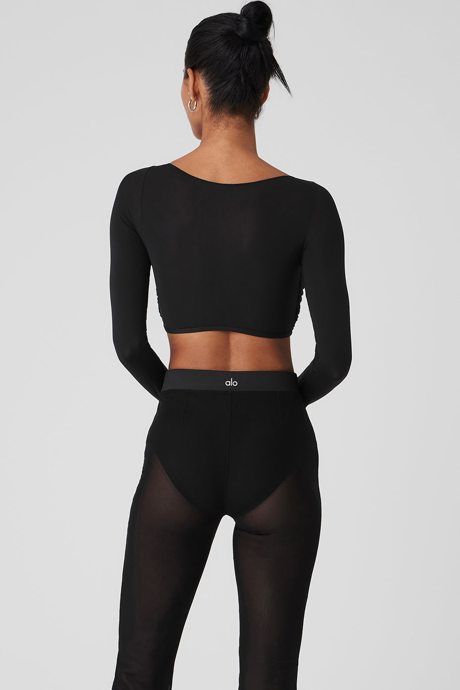 Full view of the black sheer long sleeve top paired with high-rise pants for a chic look.
