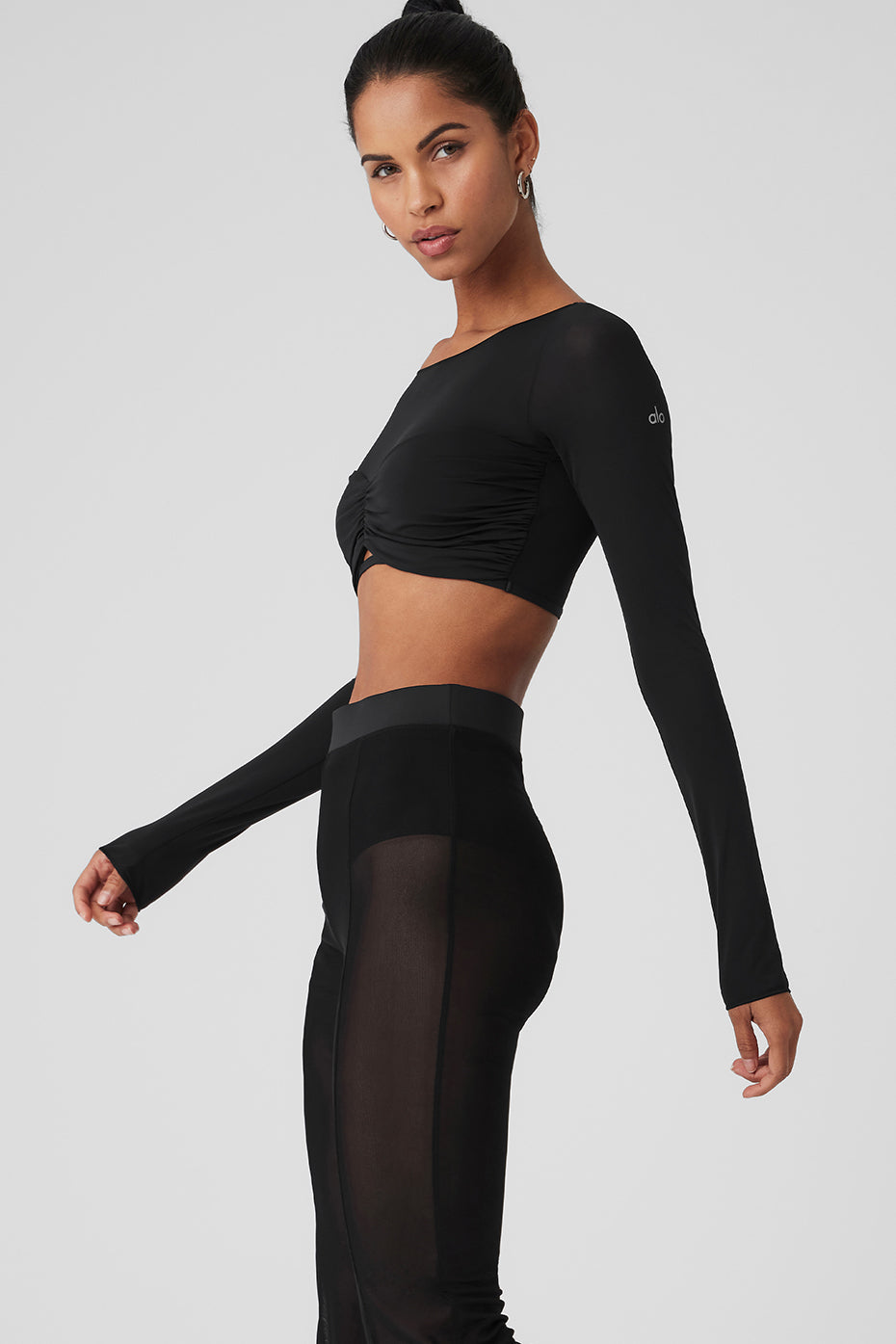 Model in a festival setting wearing the black sheer long sleeve crop top with matching pants.