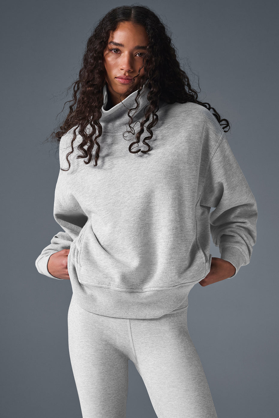 Woman wearing mock neck pullover sweatshirt with layered gold necklaces