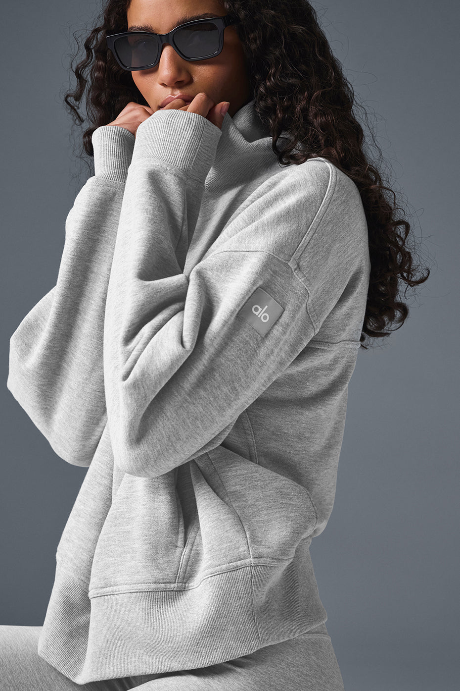 Woman wearing mock neck pullover sweatshirt with layered gold necklaces