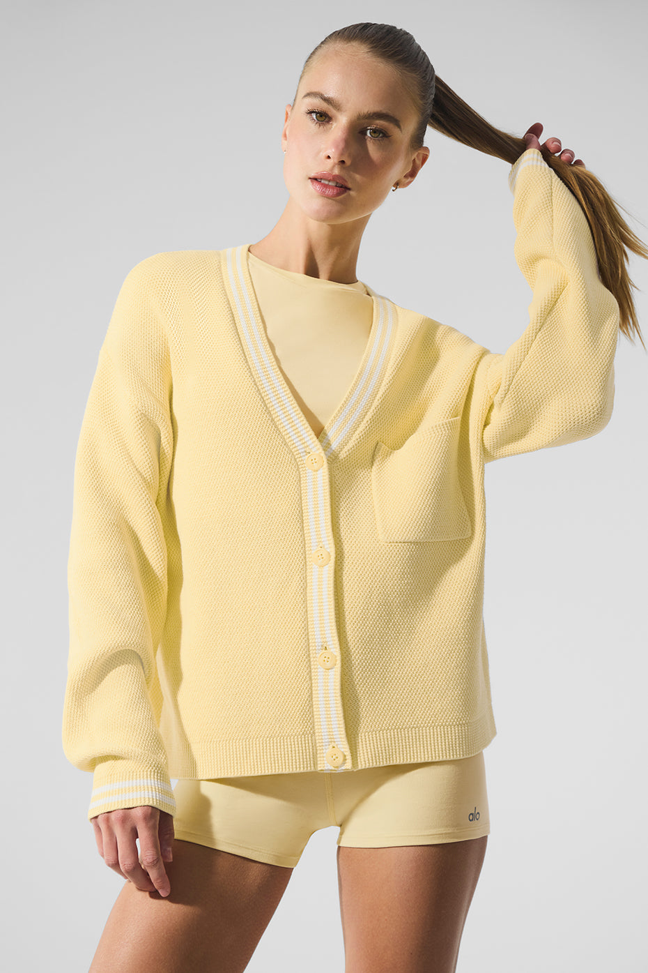 Close-up of ribbed cuffs and button details on preppy fashion style knit sweater