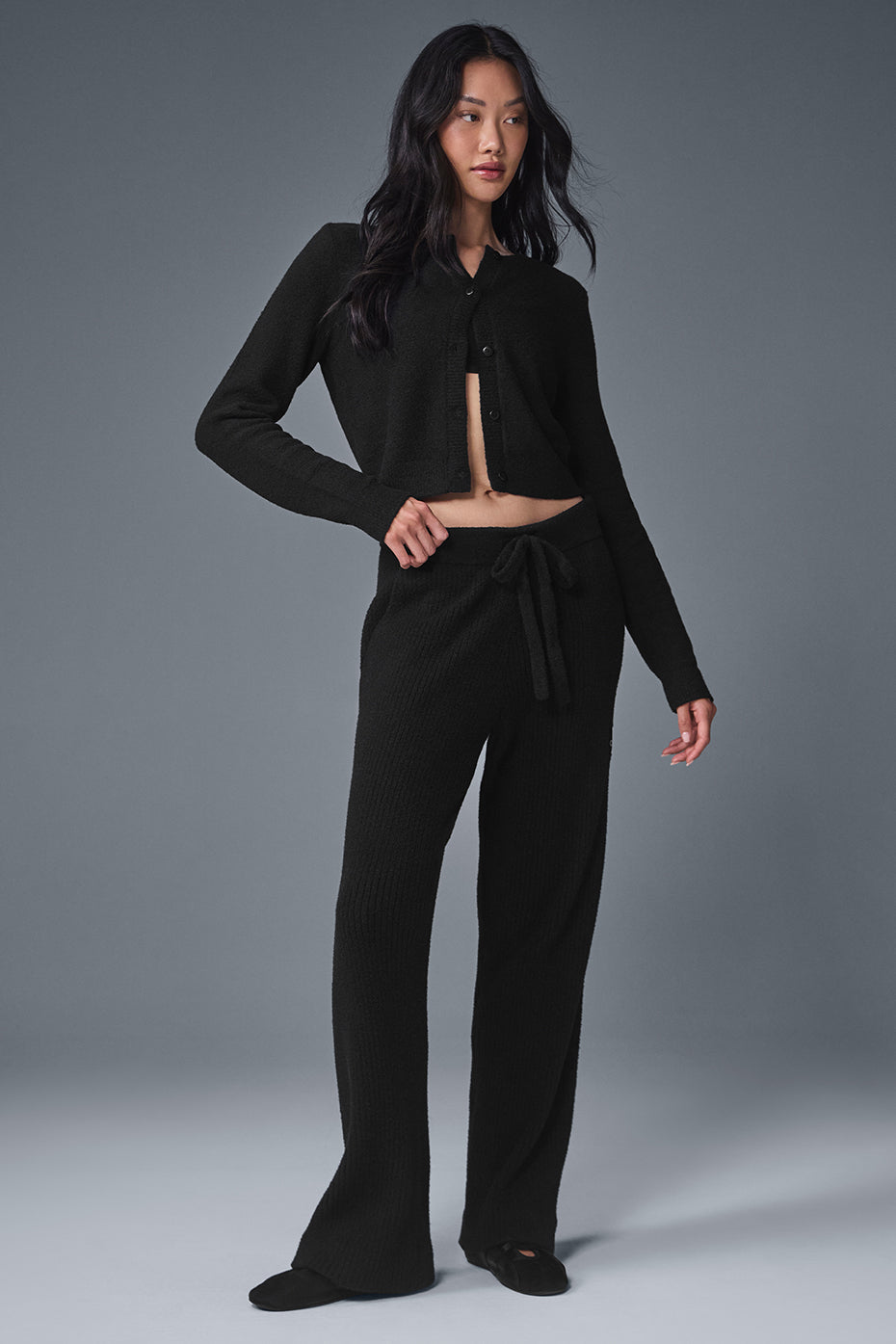 Model wearing black cropped cardigan with rolled sleeves, paired with dark jeans for everyday chic