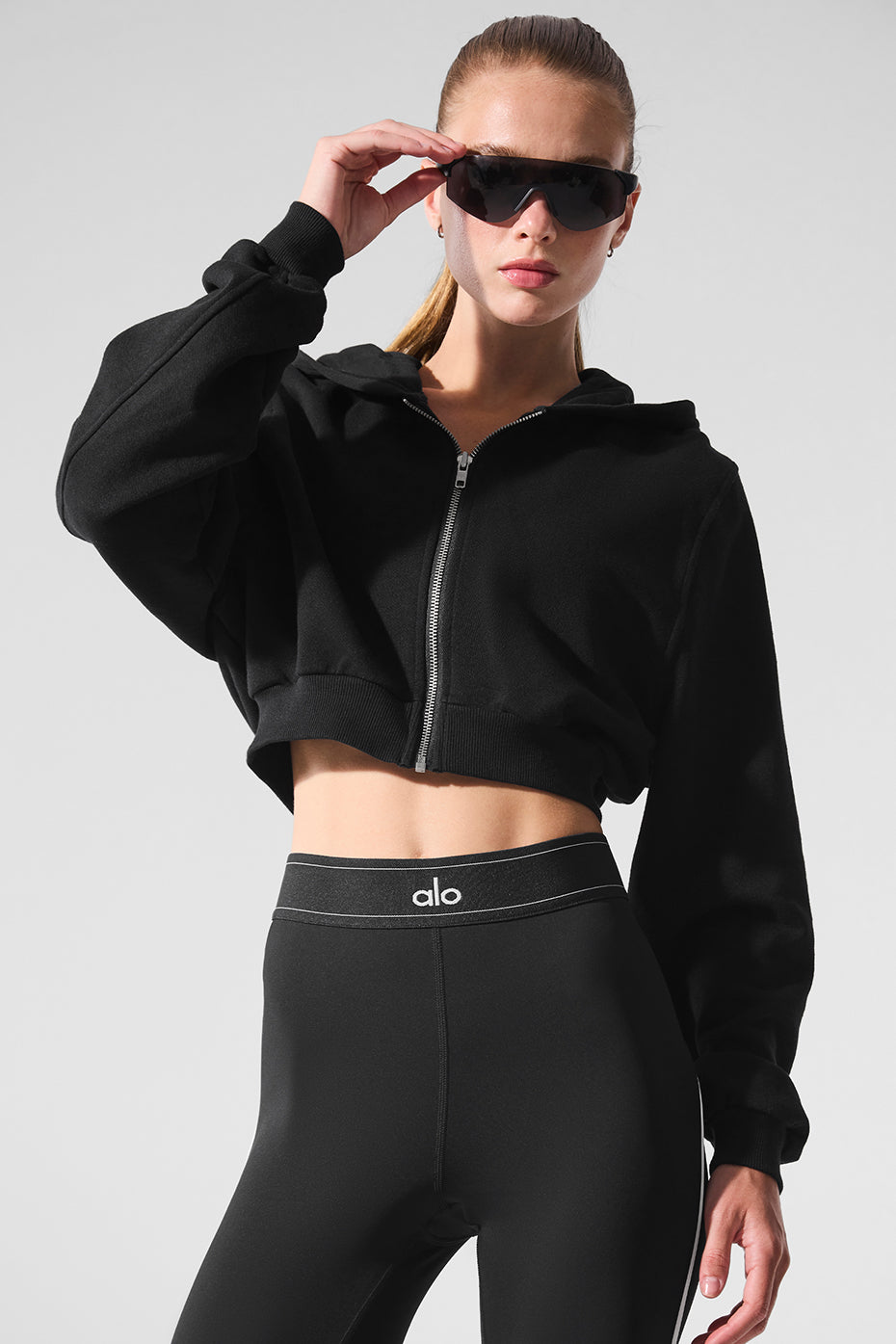 Front view of black zip up hoodie with ribbed cuffs and streamlined fit
