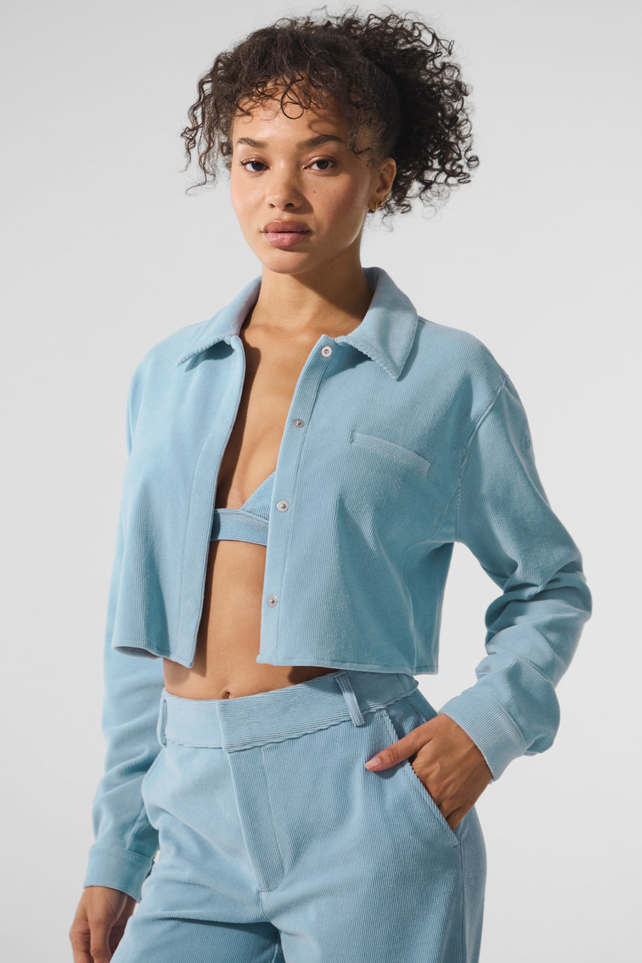 Cropped white button down shirt displayed on a hanger in natural light.
