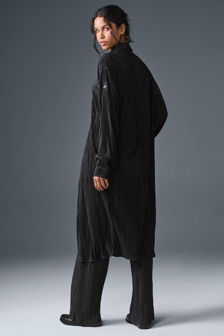 Model wearing a black plisse shirt dress at a wedding.