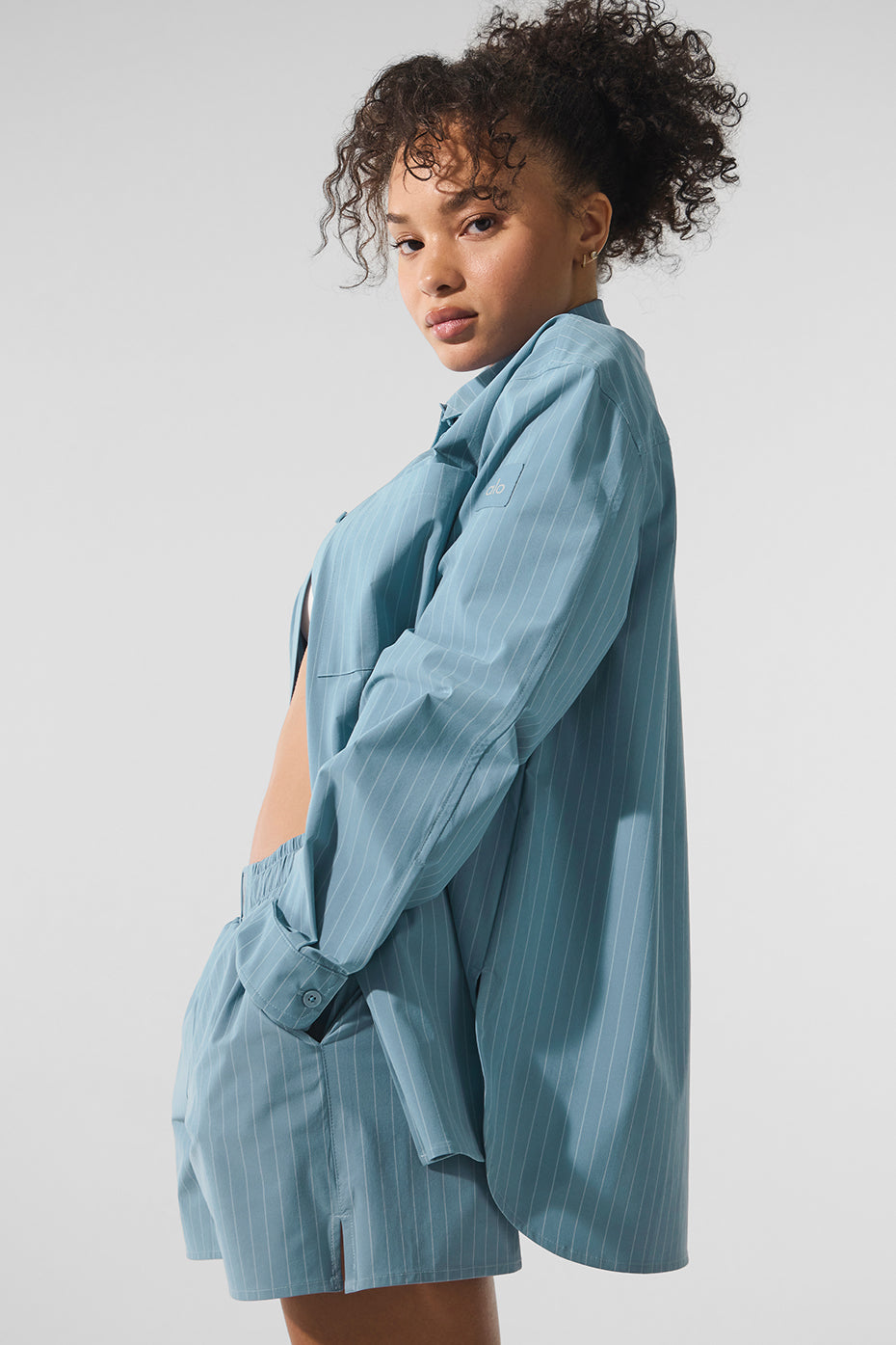 Pinstripe top displayed folded with button down shirt details visible, ideal for layering