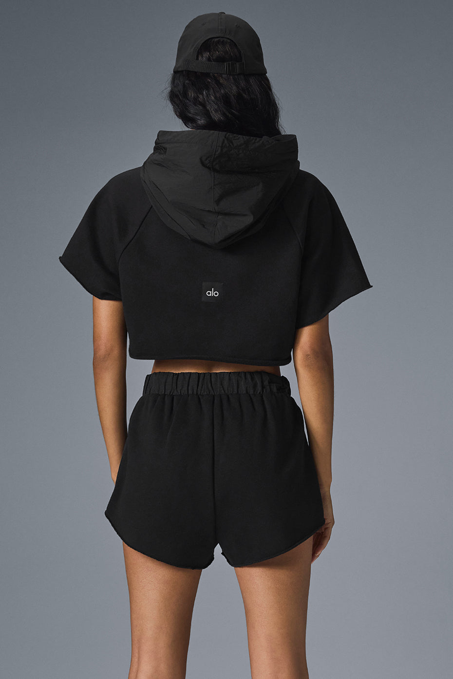 Back view of black zip up hoodie showcasing raw-cut hem.