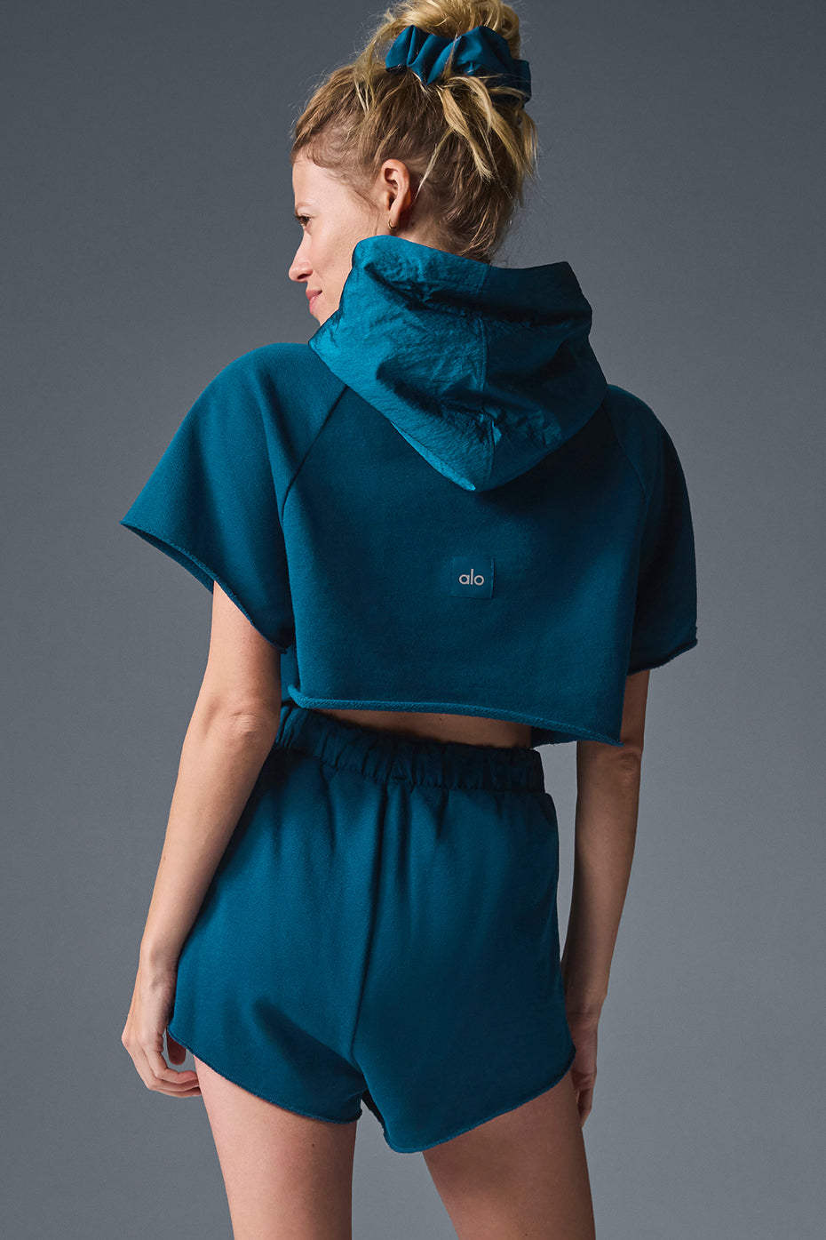 Back angle of short sleeve hoodie showing raw-cut hem and boxy shape