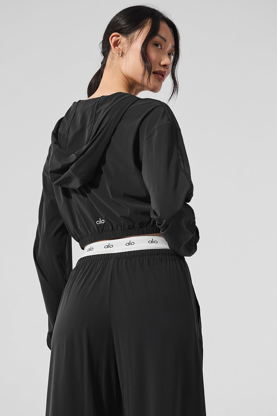 Back view highlighting the sleek satin piping of the cropped hoodie.