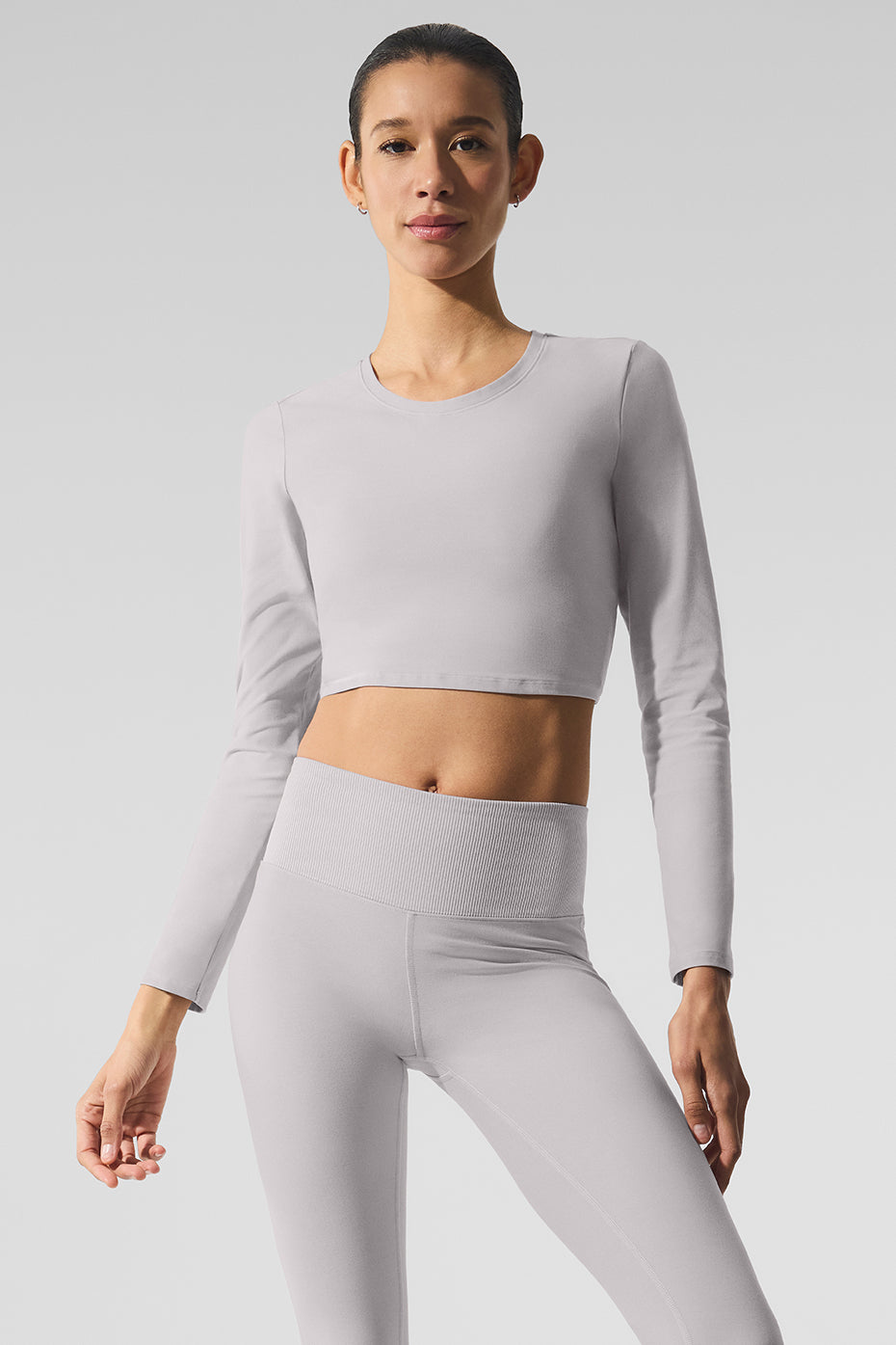 Model wearing the white long sleeve crop top during yoga class, showcasing its relaxed fit