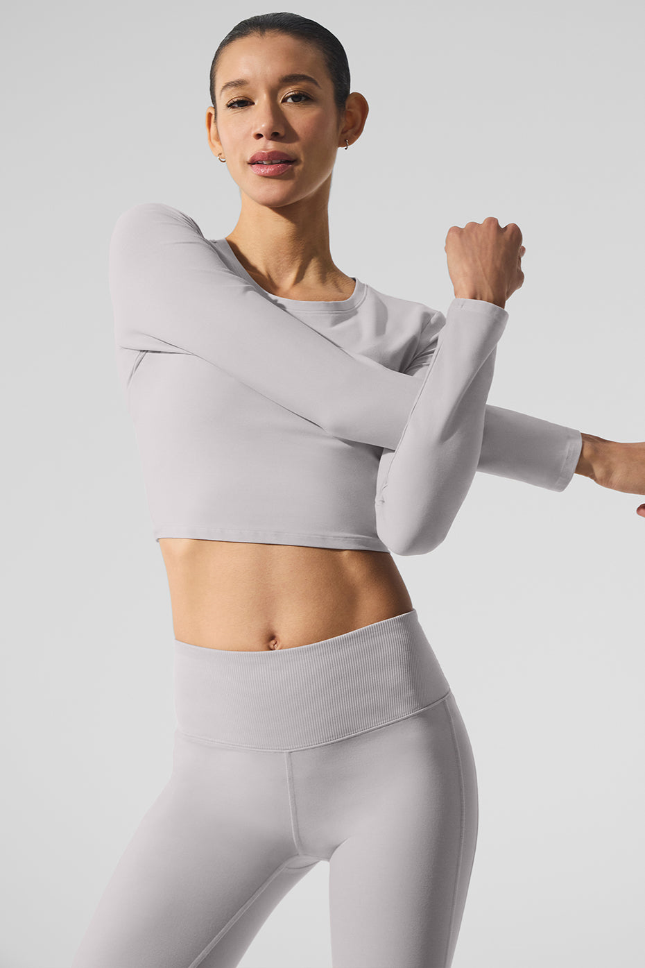 Model wearing the white long sleeve crop top during yoga class, showcasing its relaxed fit
