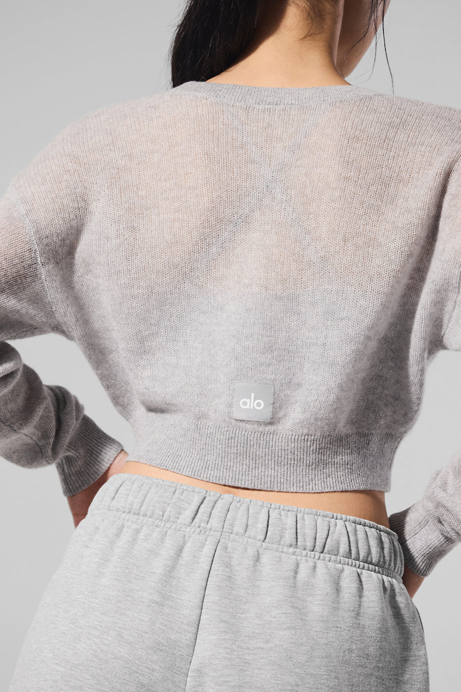 Front angle of sheer cropped cashmere cardigan layered over activewear