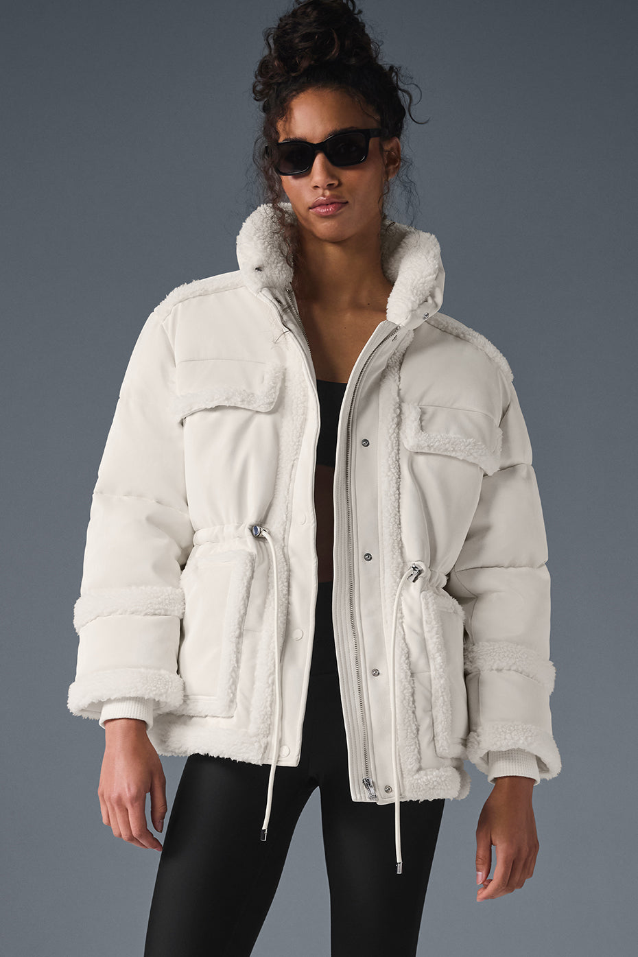 Ivory puffer jacket displayed outdoors in a snowy setting.