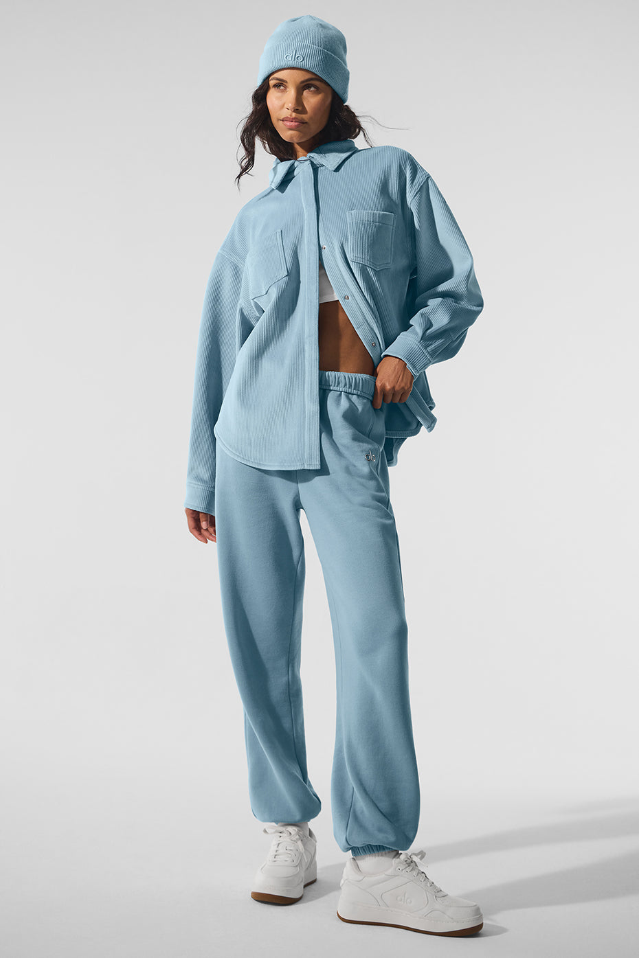 Model wearing denim shacket open over layered knit top in autumn foliage setting