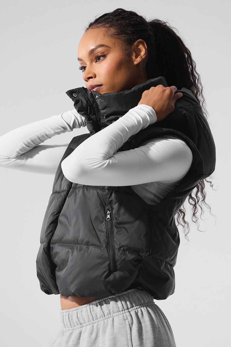 Model wearing the cropped puffer vest layered over a sweater for transitional weather