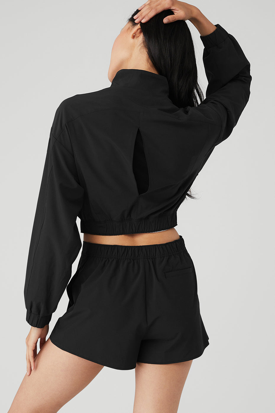 Detail shot of the cropped hem and vented back of the black leather jacket