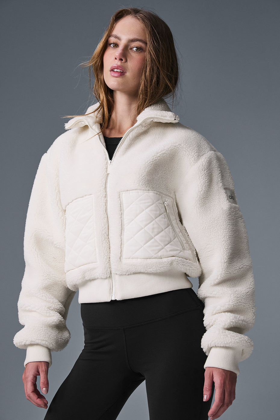 Side view of the ivory sherpa bomber jacket, highlighting the cozy fit.