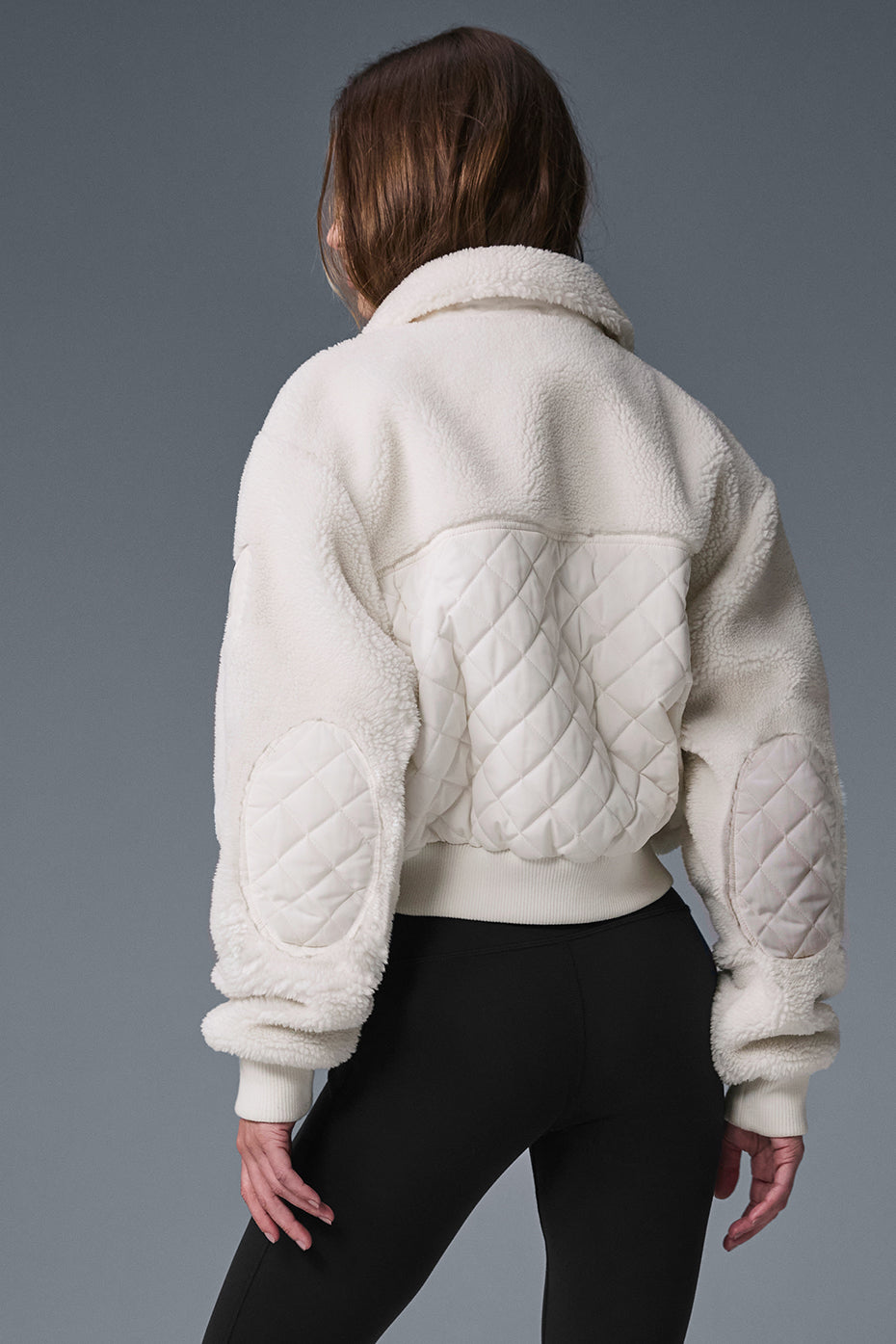 Front view of ivory sherpa bomber jacket for women, showcasing quilted patches.