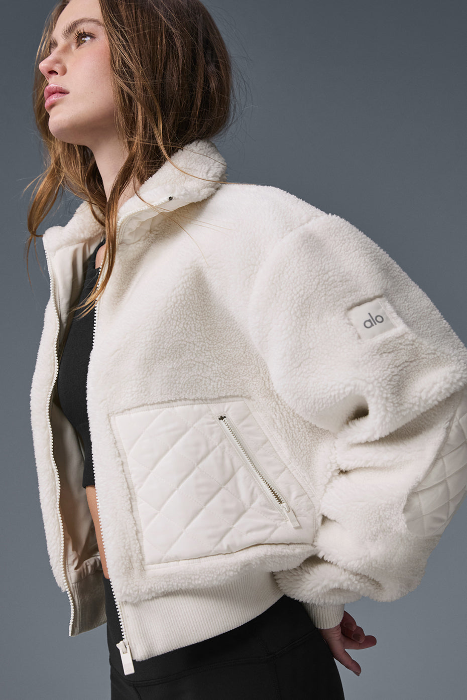 Side view of the ivory sherpa bomber jacket, highlighting the cozy fit.