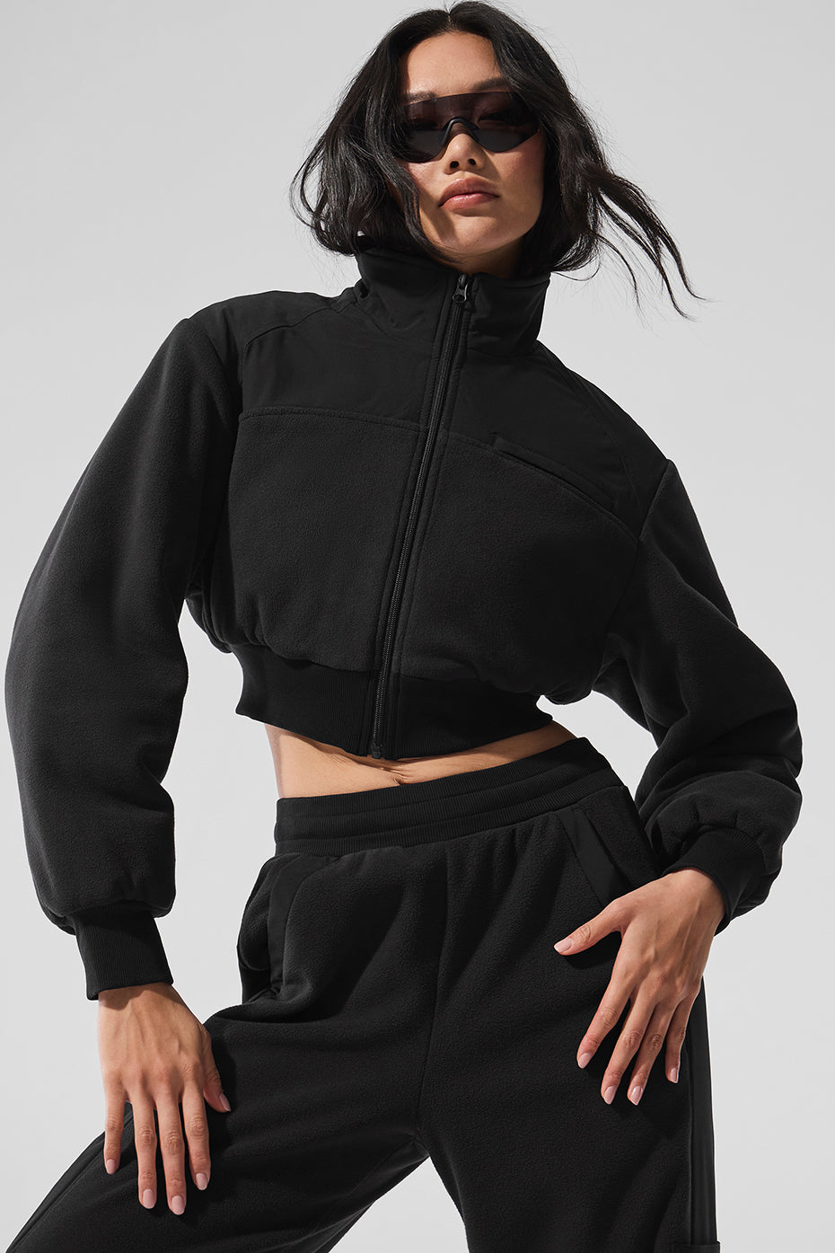Model wearing cropped polar fleece jacket with layered sweater underneath