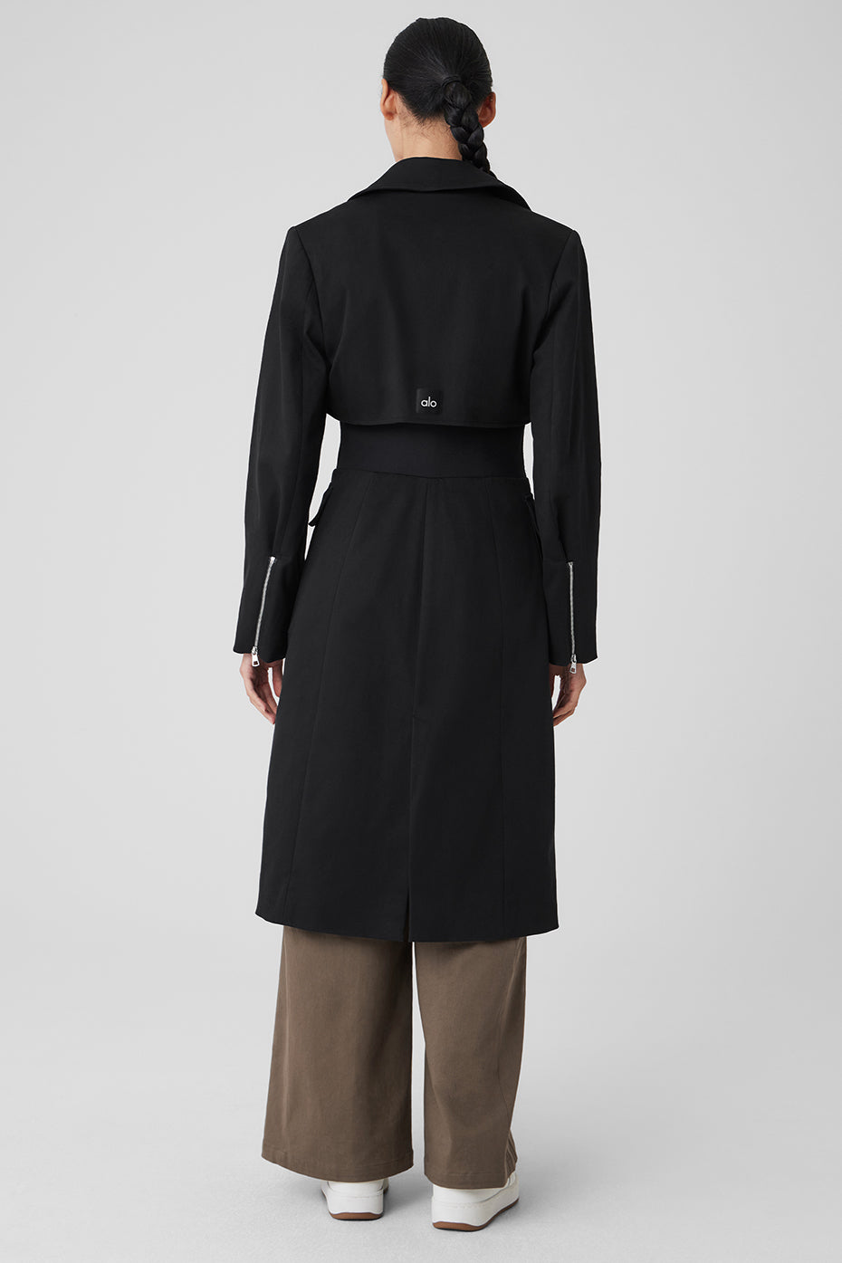 Close-up of black leather trench coat detailing and waist panel.