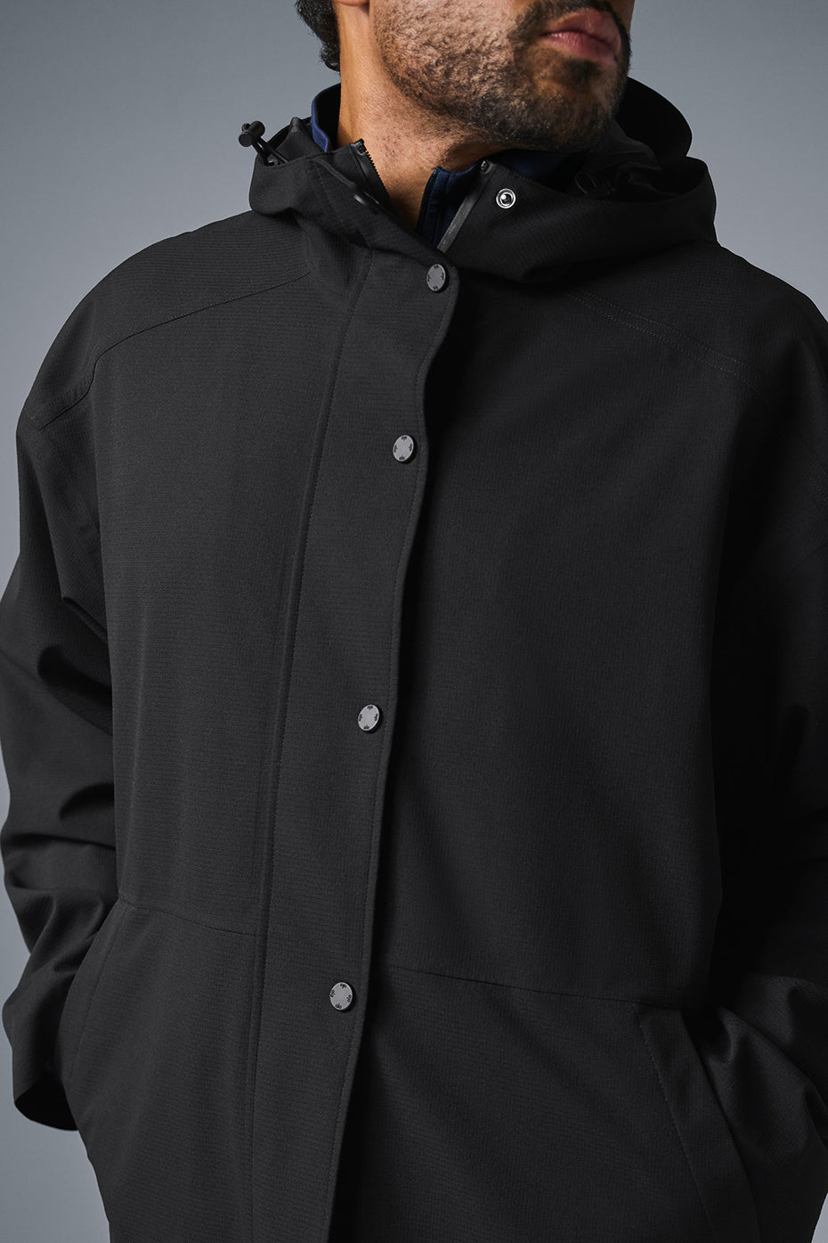Back view of the long coat, demonstrating its sleek design and waterproof material.