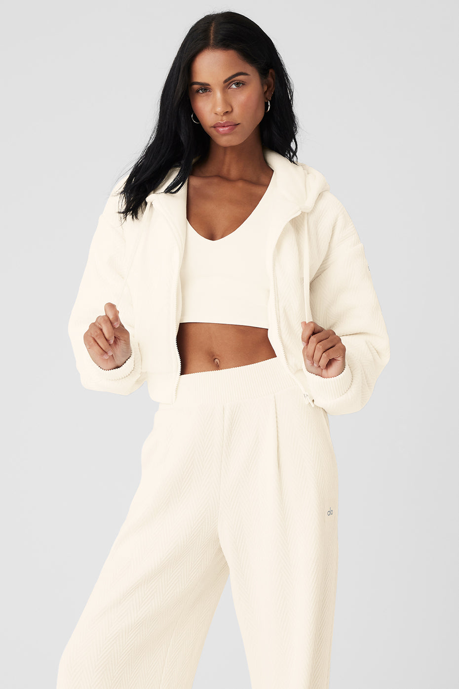 Model wearing ivory cropped jacket with hands in pockets against city backdrop