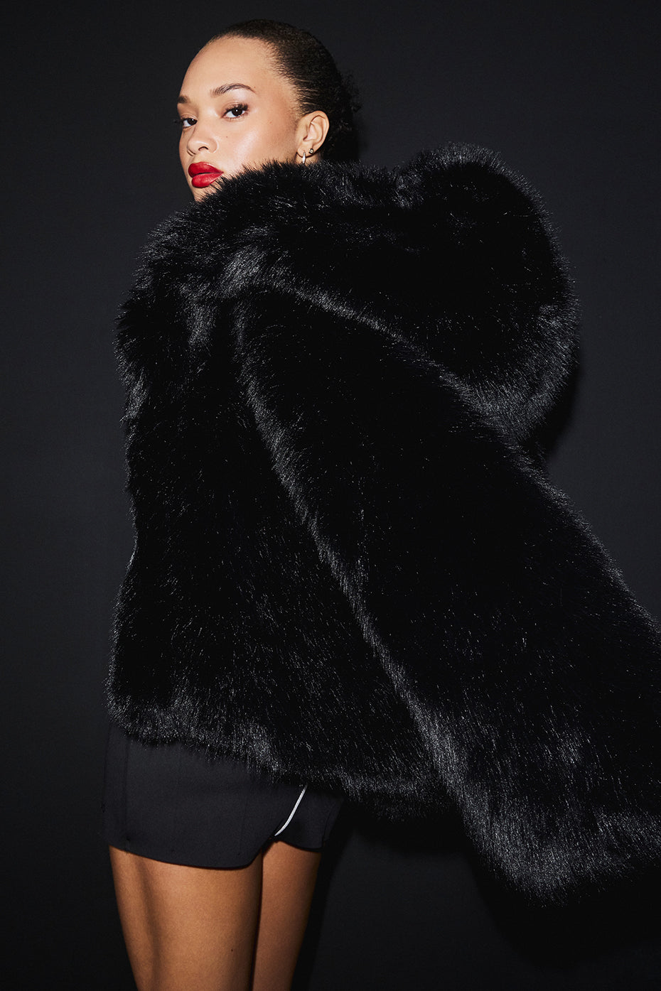 Side view of the cropped faux fur jacket highlighting its relaxed fit and bell sleeves.