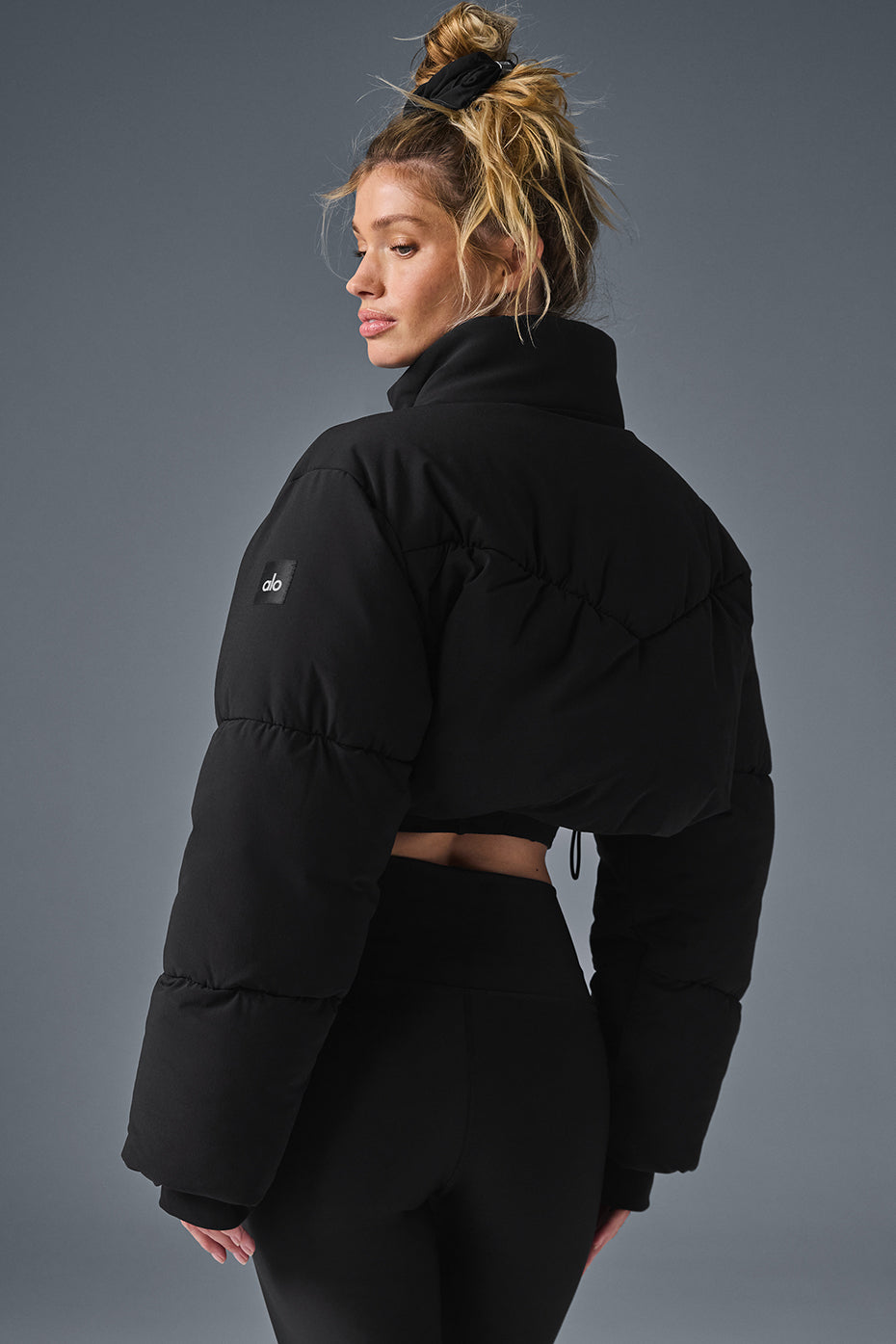 Side angle of the stylish black puffer jacket showcasing its cropped silhouette.