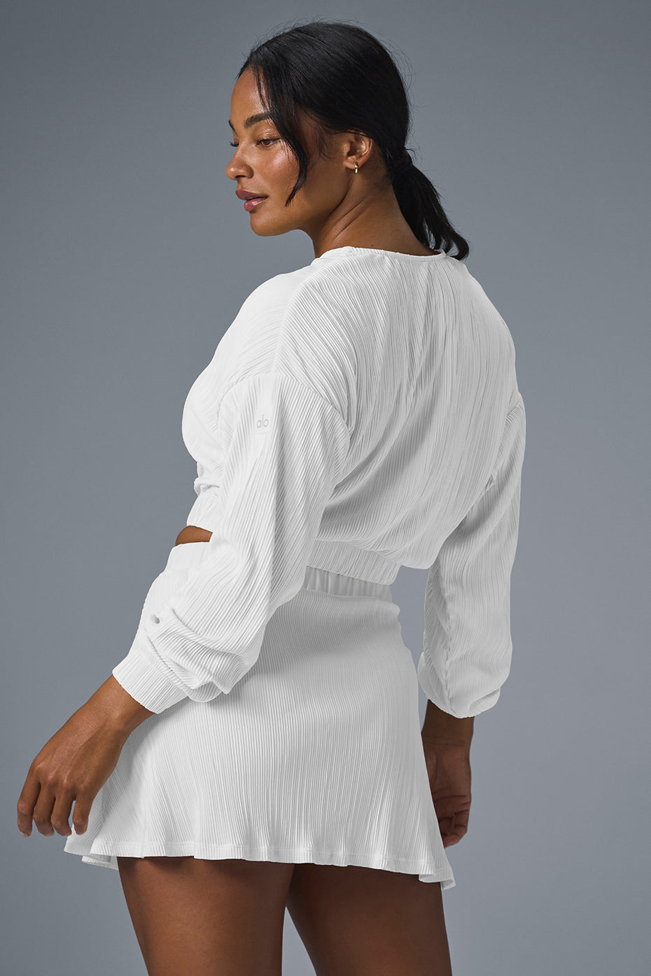 White micro plisse jacket draped over a chair, showcasing its crinkled texture