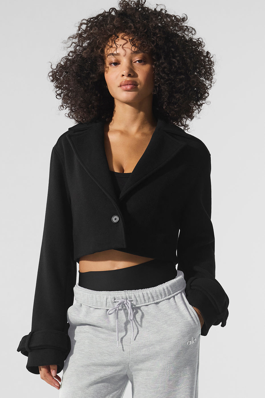 Front view of a stylish black cropped trench coat on a model.