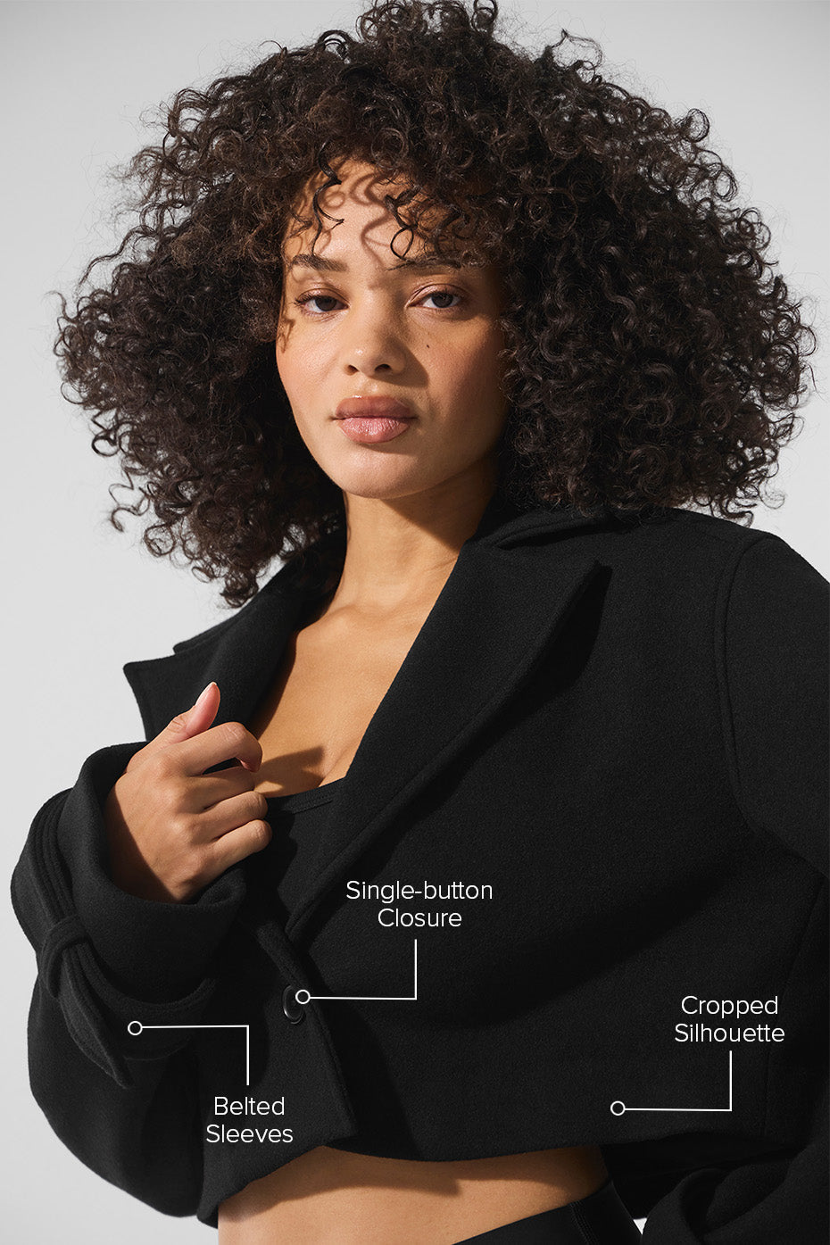 Close-up of the belted sleeves on a black wool trench coat.