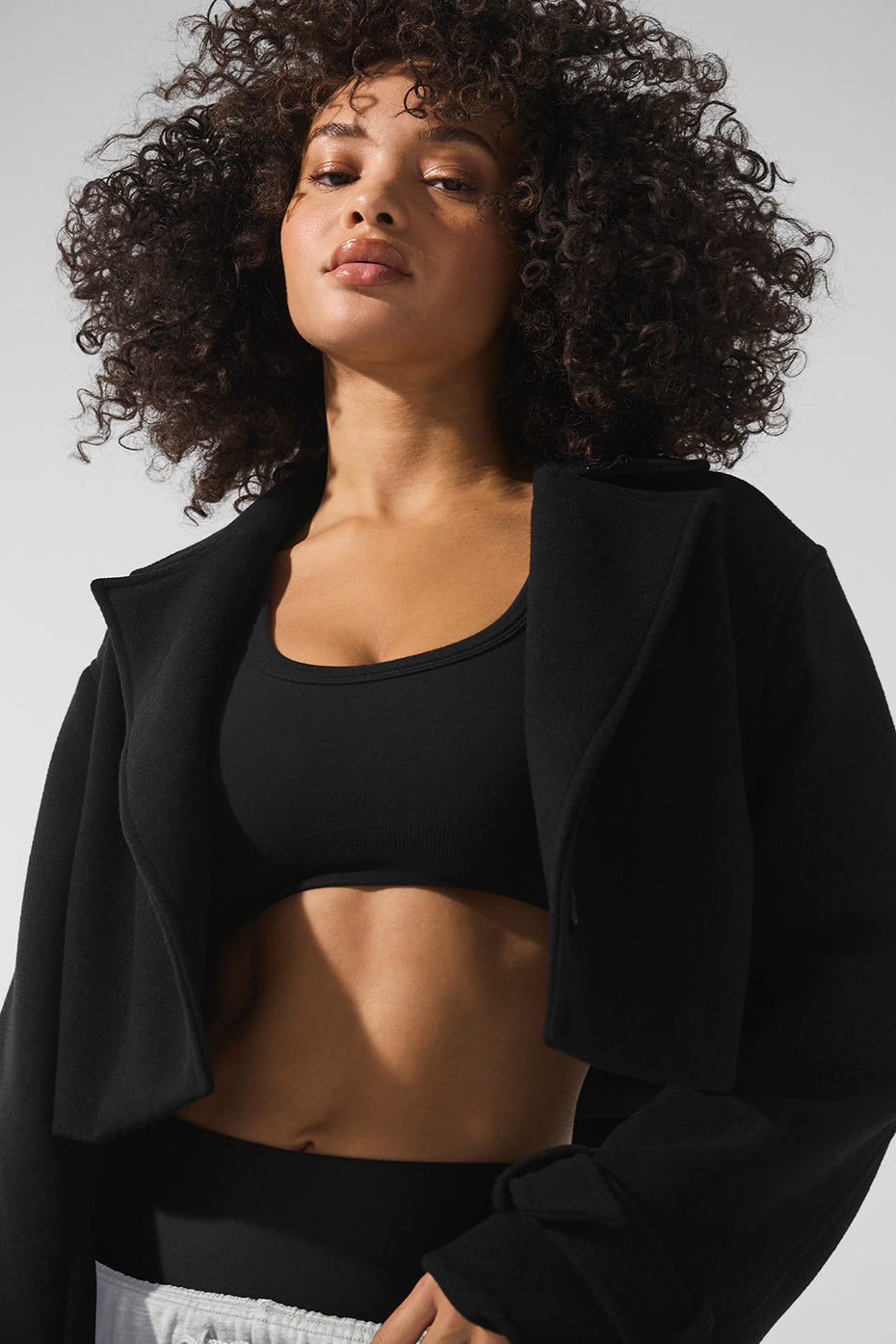 Front view of a stylish black cropped trench coat on a model.