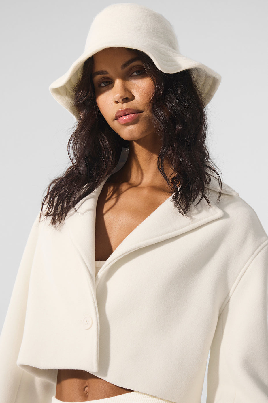 Front view of the ivory wool cropped trench coat on a model