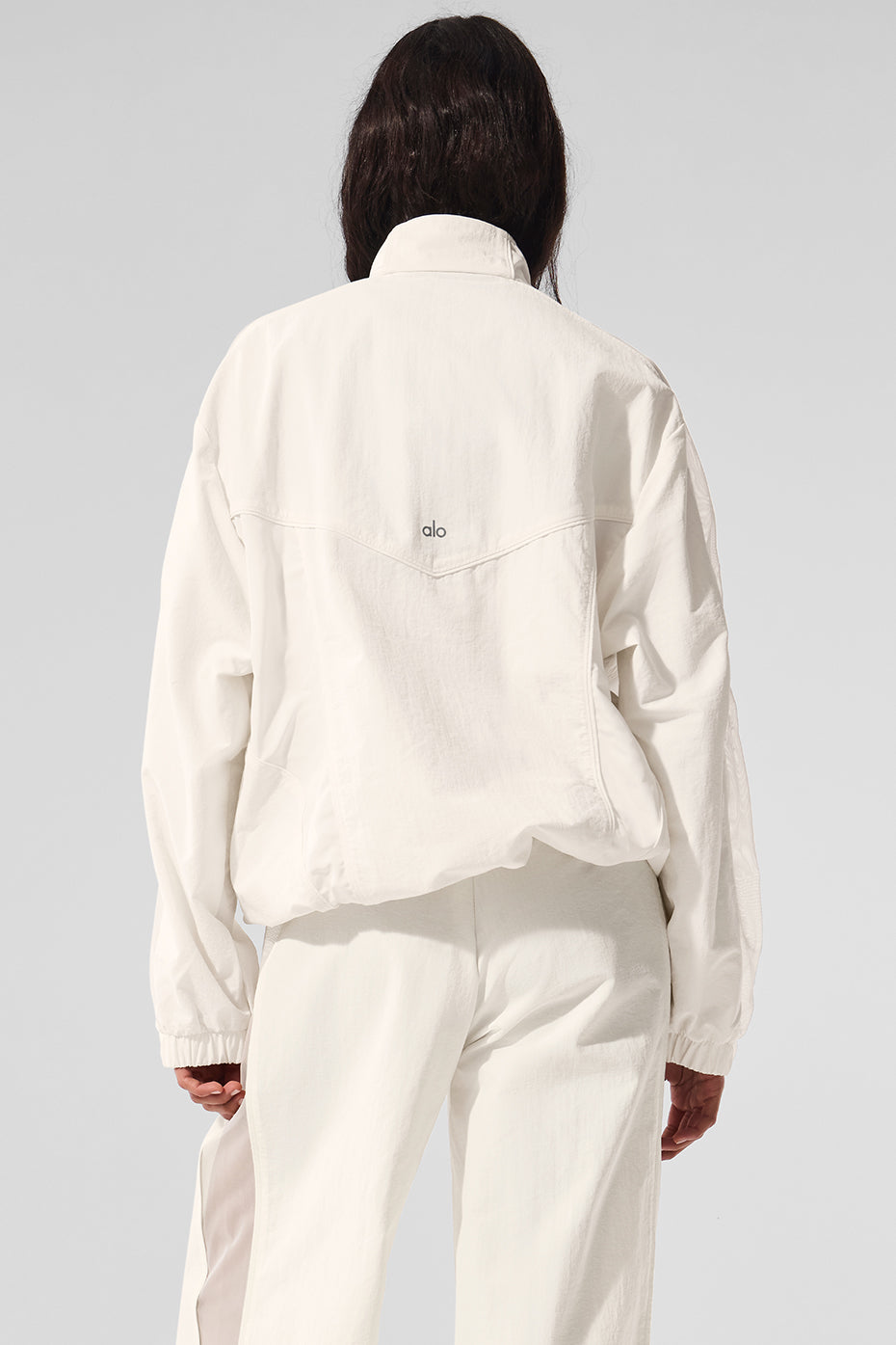 Woman wearing Origin ivory track jacket unzipped over activewear