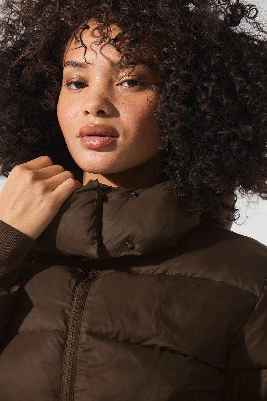 Woman walking outdoors in a city wearing a black puffer jacket, winter coat style