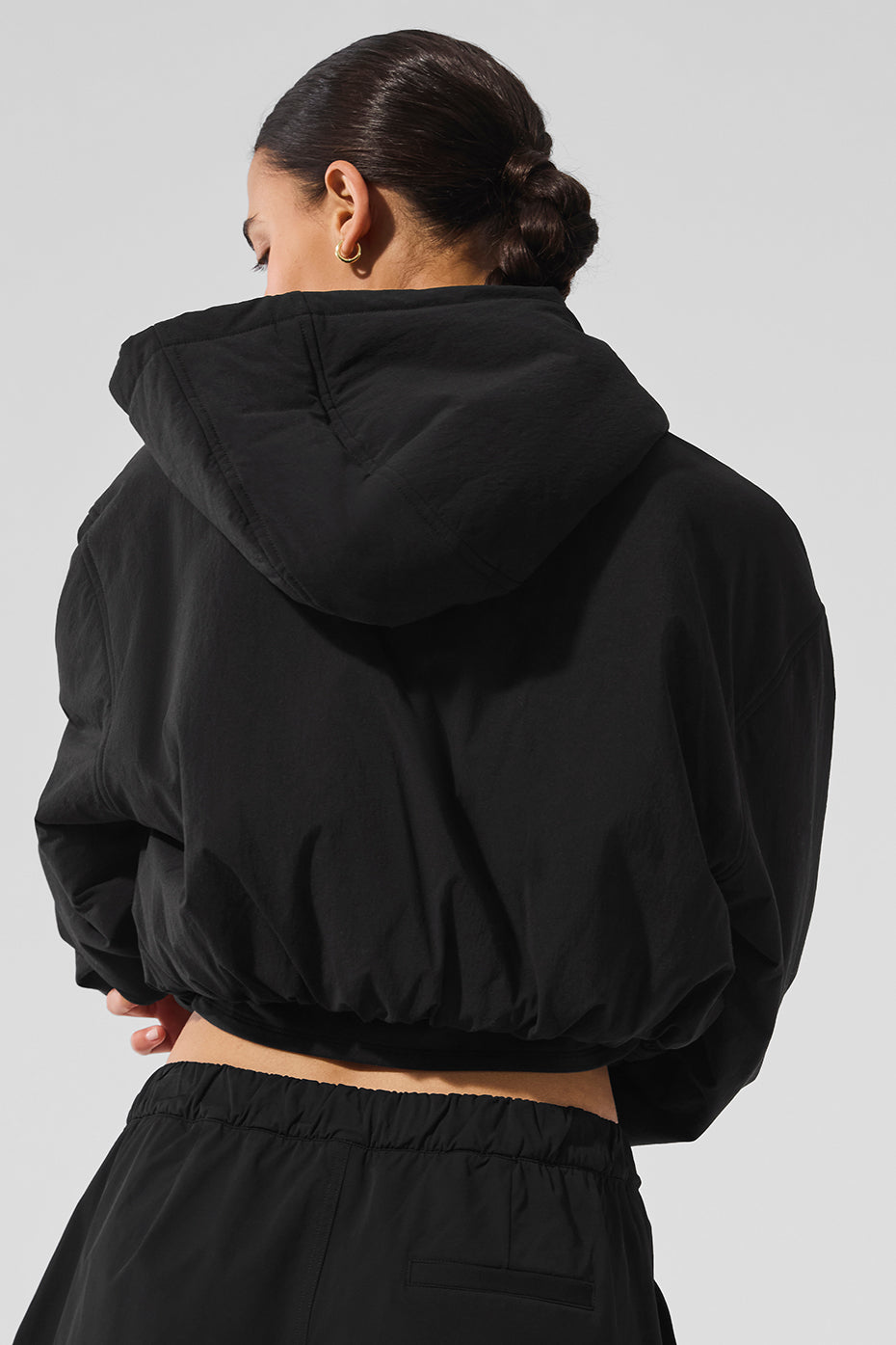 Cropped black hoodie showcasing its unique bubbled cuffs and relaxed fit.