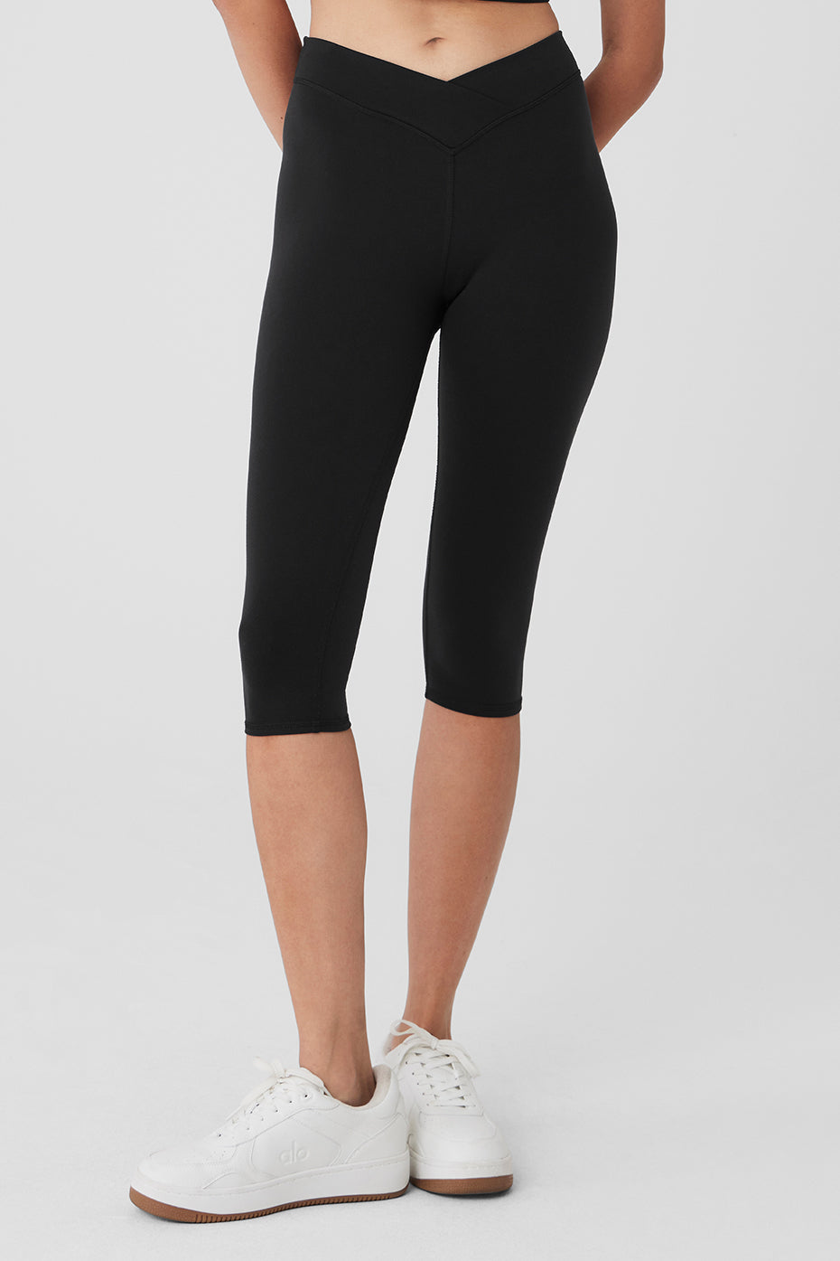 Model wearing black capri leggings with V-cut waist in yoga studio