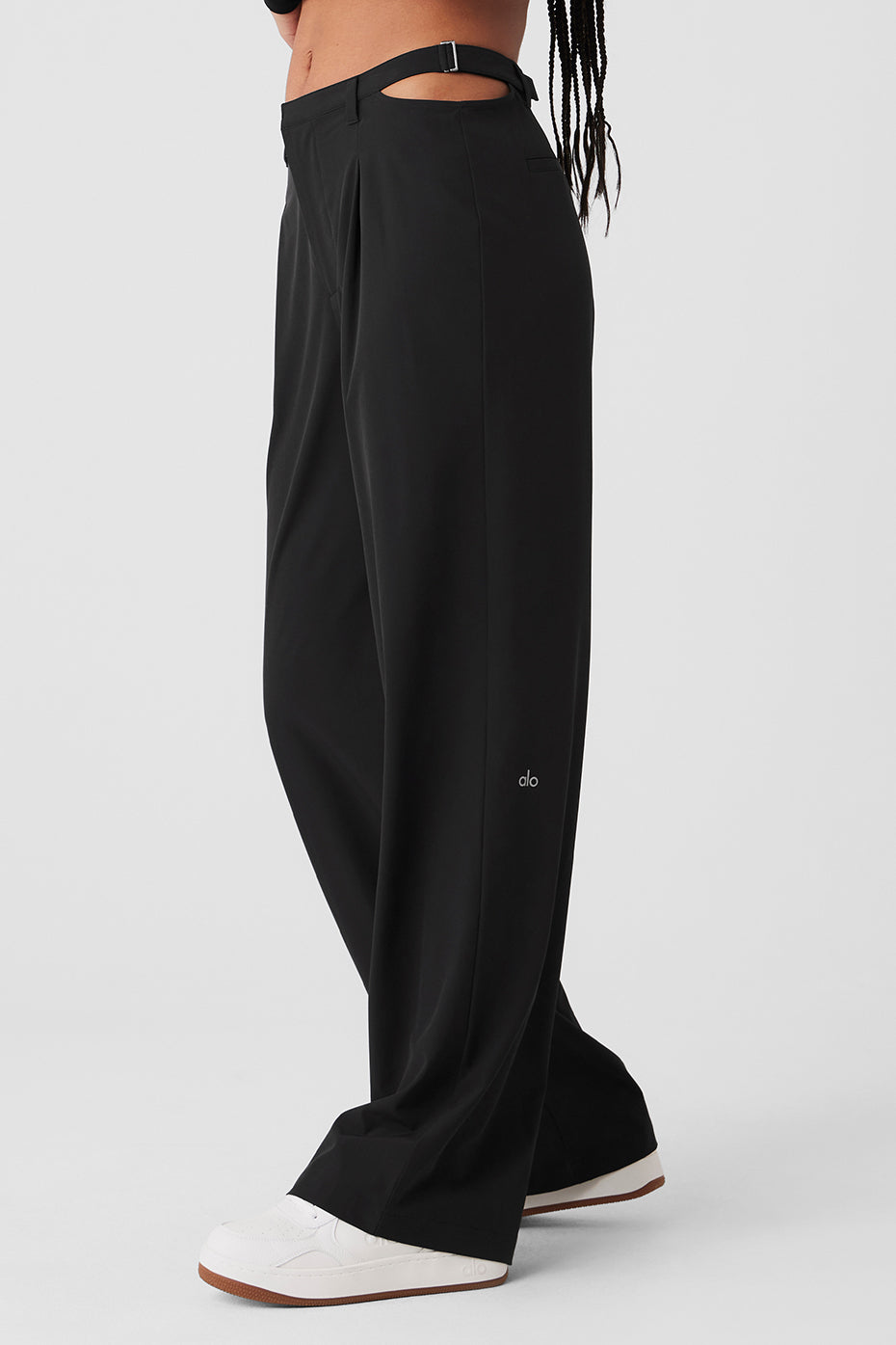 Front view of stylish black mid-rise trousers with cut outs and side buckles.