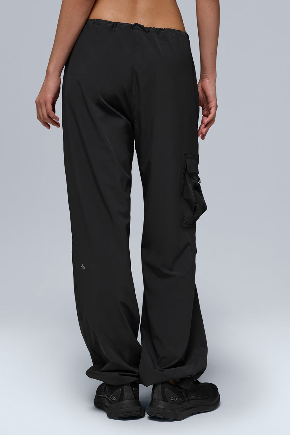 Side view showcasing adjustable bungee hems of black cargo pants.